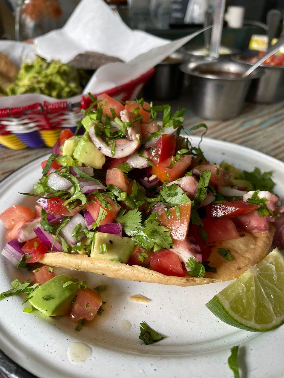 A taco with a lime wedge on a plate.