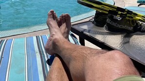 A poolside view with a lounge chair, a pair of feet resting on the edge, and a table with a pair of shoes. - Tortuga Bay TBB 2502 (San José del Cabo)