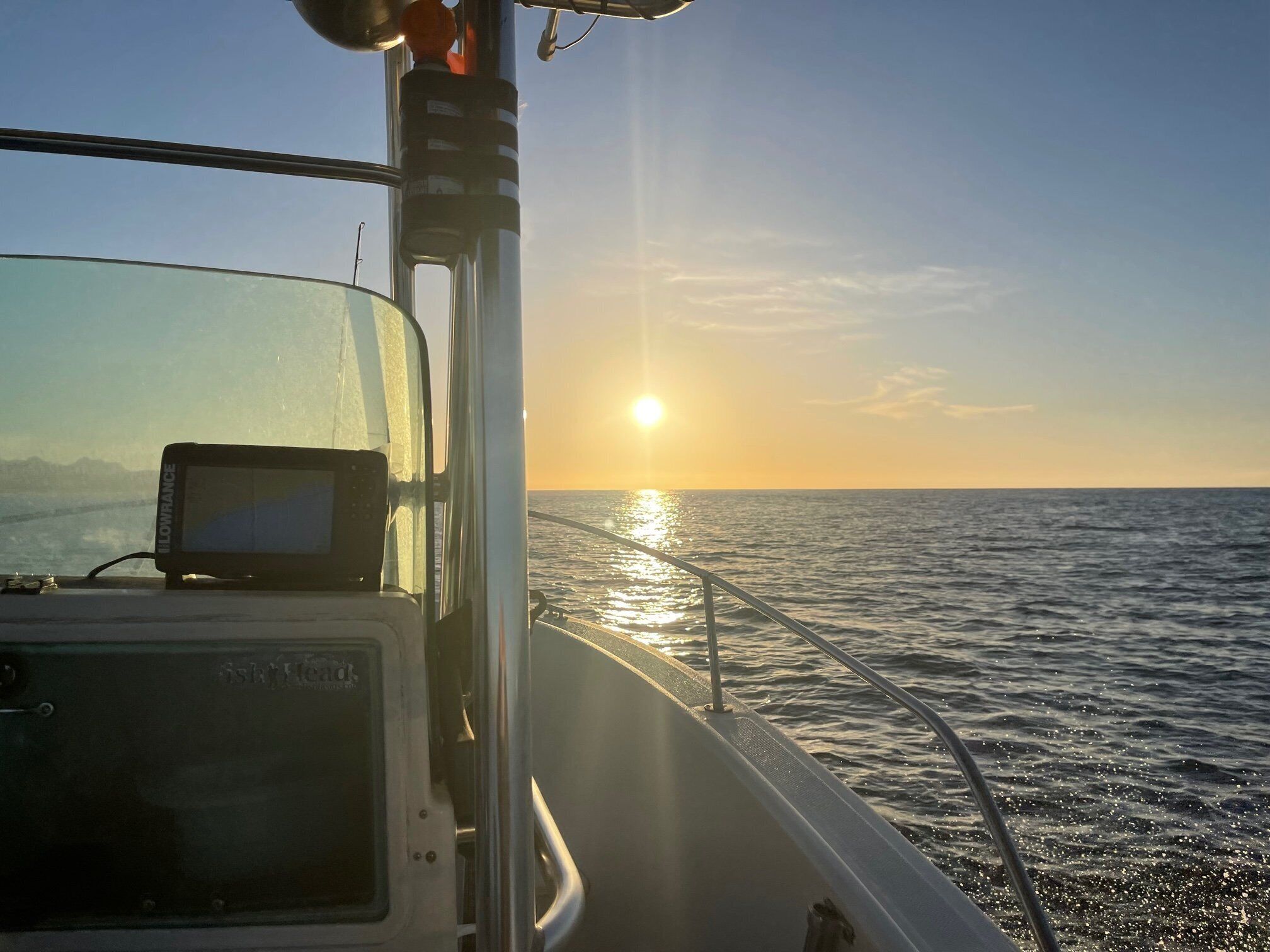 Schiffsinnenraum mit Armaturenbrett und Blick auf den Sonnenuntergang über dem Meer.