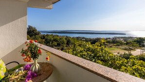 A balcony with a view of a coastal landscape, including a body of water and distant hills. - Pet friendly apartment in Rab with WiFi (Rab)
