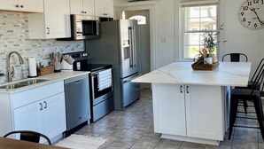 A modern kitchen with white cabinets, stainless steel appliances, and a large island.