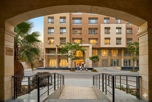 A multi-story hotel with a central courtyard, a covered entrance, and a palm tree.