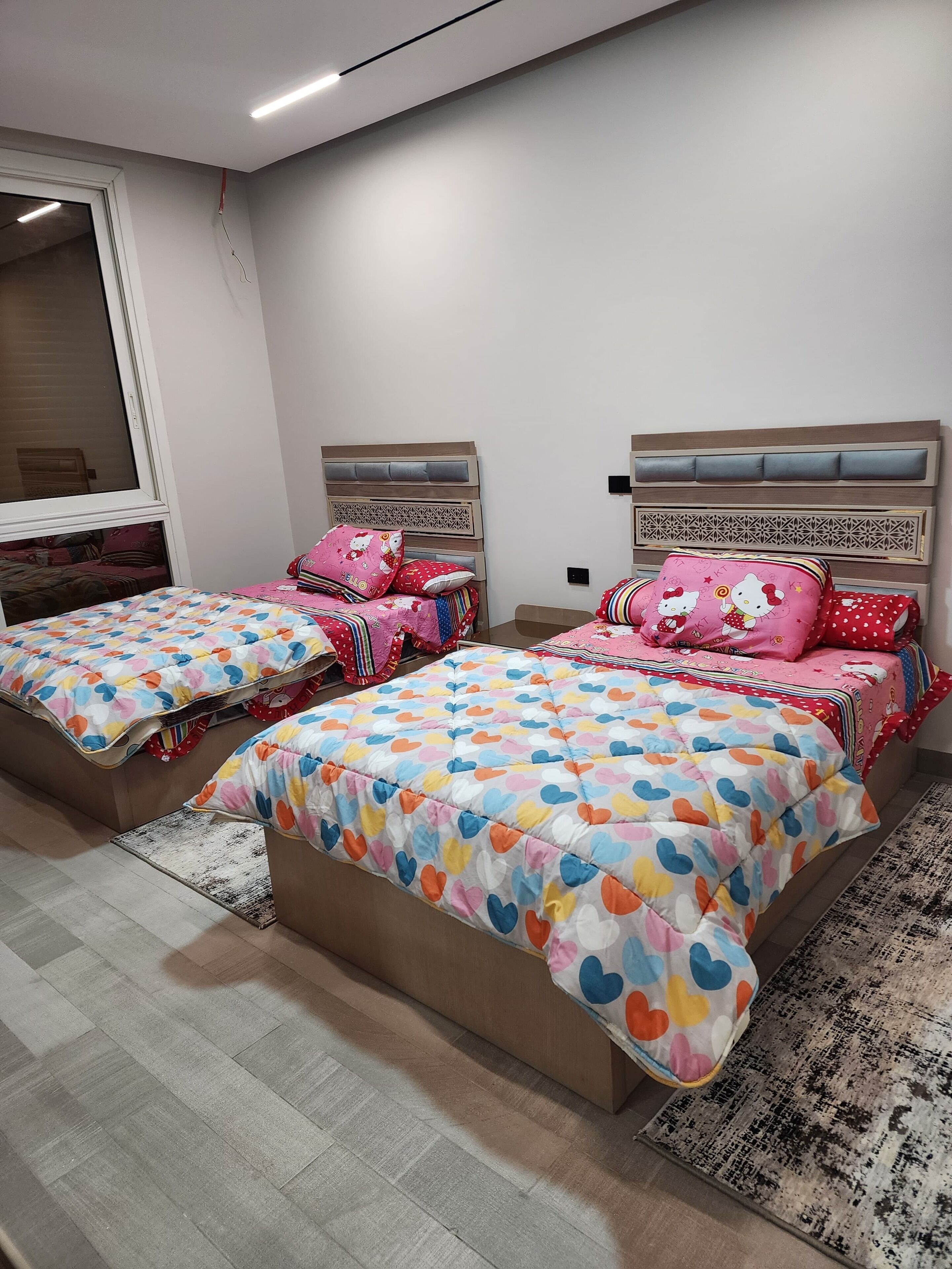 Une chambre à coucher avec deux lits, chacun recouvert d’une couvre-lit à motifs et agrémenté d’oreillers assortis.