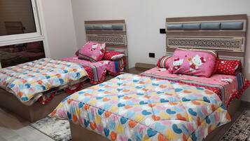 Une chambre à coucher avec deux lits, chacun recouvert d’une couvre-lit à motifs et agrémenté d’oreillers assortis.