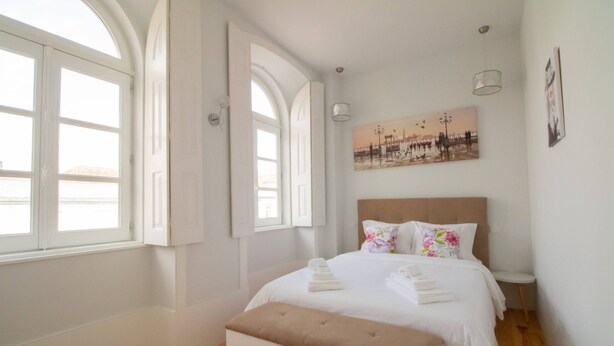 Un dormitorio con una cama grande, un banco y un cuadro en la pared.