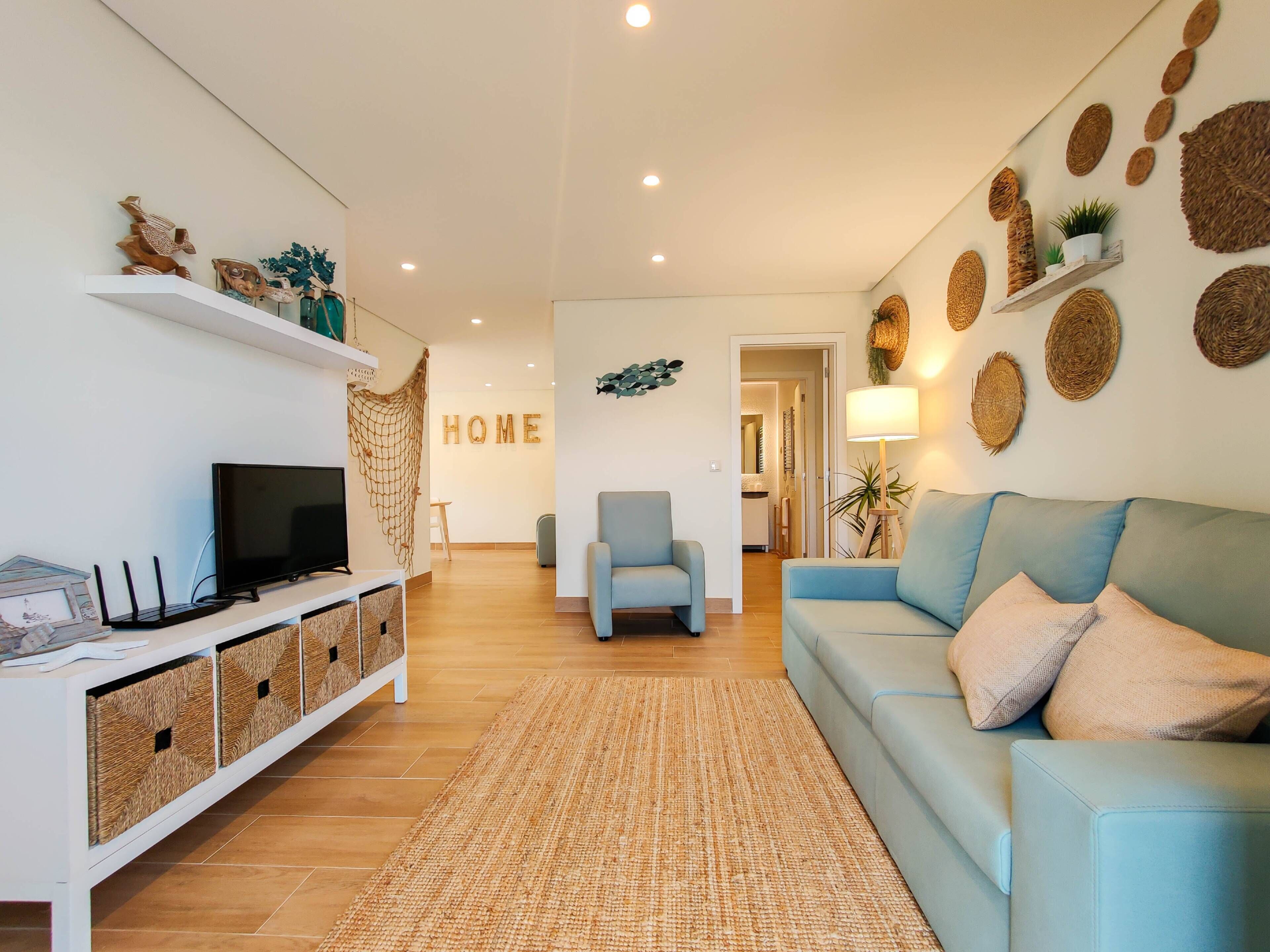 A modern living room with a sofa, a TV, and decorative items on shelves.