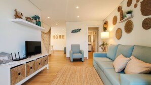 Una sala de estar moderna con un sofá, un televisor y objetos decorativos en estanterías.