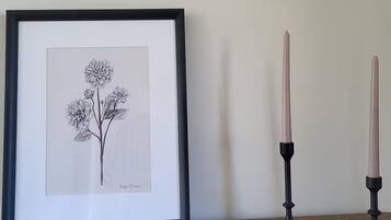 Een ingelijste botanische tekening op een houten oppervlak, met aan weerszijden twee zwarte kandelaars.