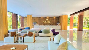 A modern hotel lobby with a reception desk, plush seating, and a view of greenery outside. - Luxtalay Khanom Hotel (Khanom)