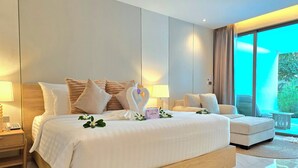 Una habitación de hotel moderna con una cama grande, un sofá, una mesita y vistas a zonas verdes por la ventana.