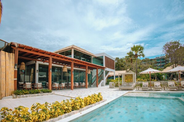 A poolside area with a covered seating area, outdoor furniture, and a clear view of the pool.