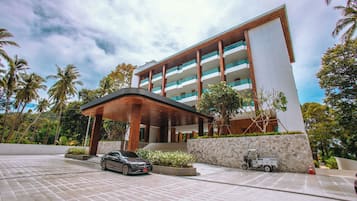 A modern hotel with a covered entrance, a car parked in front, and a golf cart nearby.