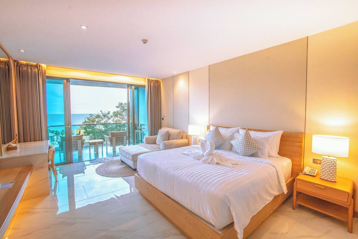 Une chambre d’hôtel moderne dotée d’un grand lit, d’un coin salon avec vue et d’un balcon.