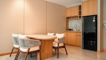 A modern kitchen with a round dining table, six chairs, wooden cabinets, and a black refrigerator.