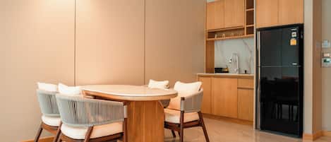 A modern kitchen with a round dining table, six chairs, wooden cabinets, and a black refrigerator.