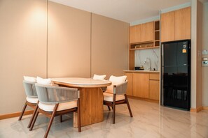 A modern kitchen with a round dining table, six chairs, wooden cabinets, and a black refrigerator. - Luxtalay Khanom Hotel (Khanom)