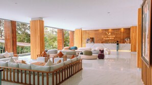 A spacious lobby with a reception desk, comfortable seating areas, and large windows offering a view of the outdoors. - Luxtalay Khanom Hotel (Khanom)