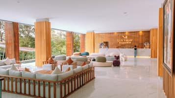 A spacious lobby with a reception desk, comfortable seating areas, and large windows offering a view of the outdoors.