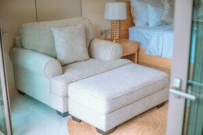 A bedroom with a sofa bed, a bedside table with a lamp, and a bed with pillows and a blanket. - Luxtalay Khanom Hotel (Khanom)