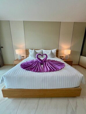 A neatly made bed with a heart-shaped towel arrangement and a wooden headboard.