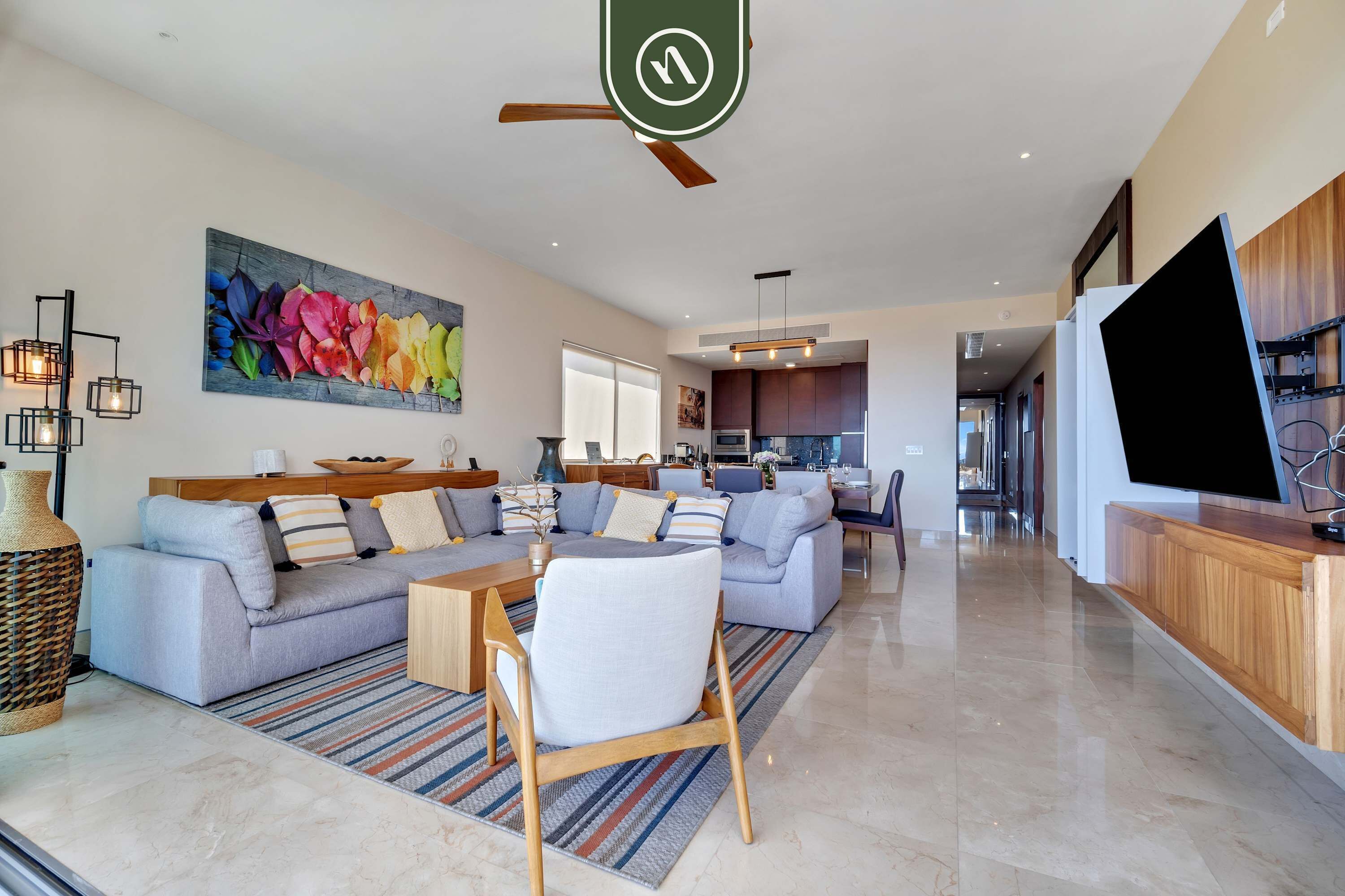 A modern living room with a sofa set, a dining table with chairs, a TV, and a kitchen in the background.