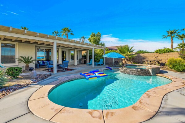 A swimming pool with lounge chairs and a covered patio area.