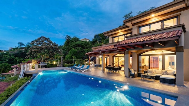 Ein modernes Haus mit Swimmingpool, Sitzgelegenheiten im Freien und einer überdachten Terrasse.