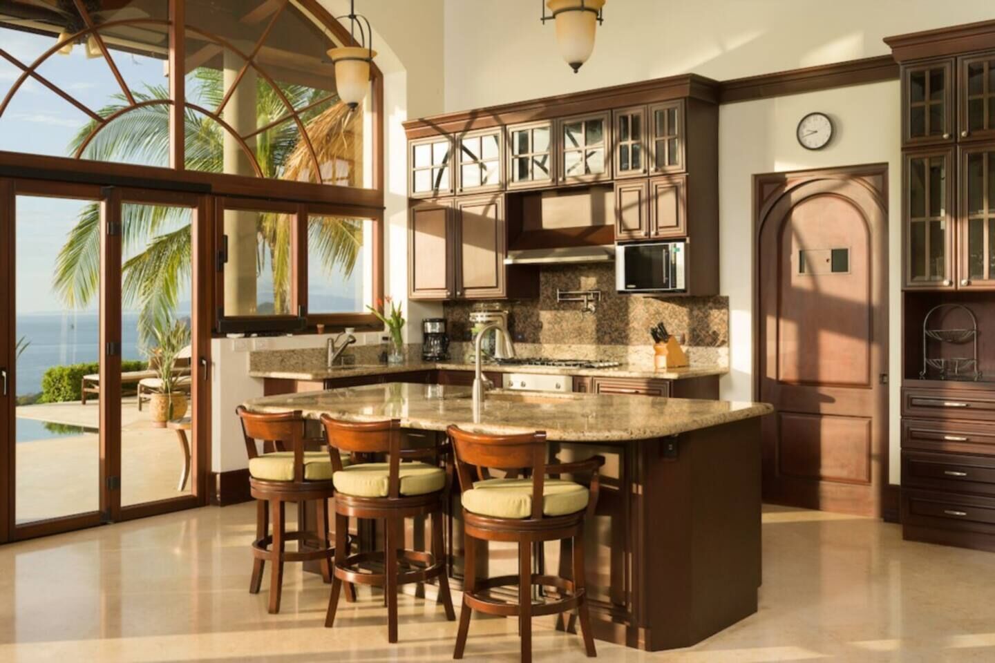 A kitchen with a large island, bar stools, and a view of the ocean.