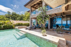 A modern house with a swimming pool, outdoor seating, and a view of the ocean. - Playa Hermosa Villa • 3BR • Infinity Pool & Swim-Up Bar • Ocean Views (Playa Hermosa)