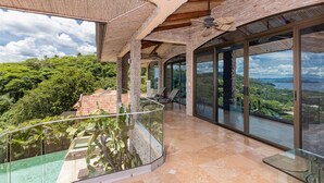 A modern villa with a glass balcony overlooking lush greenery and a scenic view. - Playa Hermosa Villa • 3BR • Infinity Pool & Swim-Up Bar • Ocean Views (Playa Hermosa)