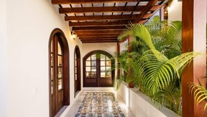 A hallway with a tiled floor, wooden doors, and a wooden ceiling.