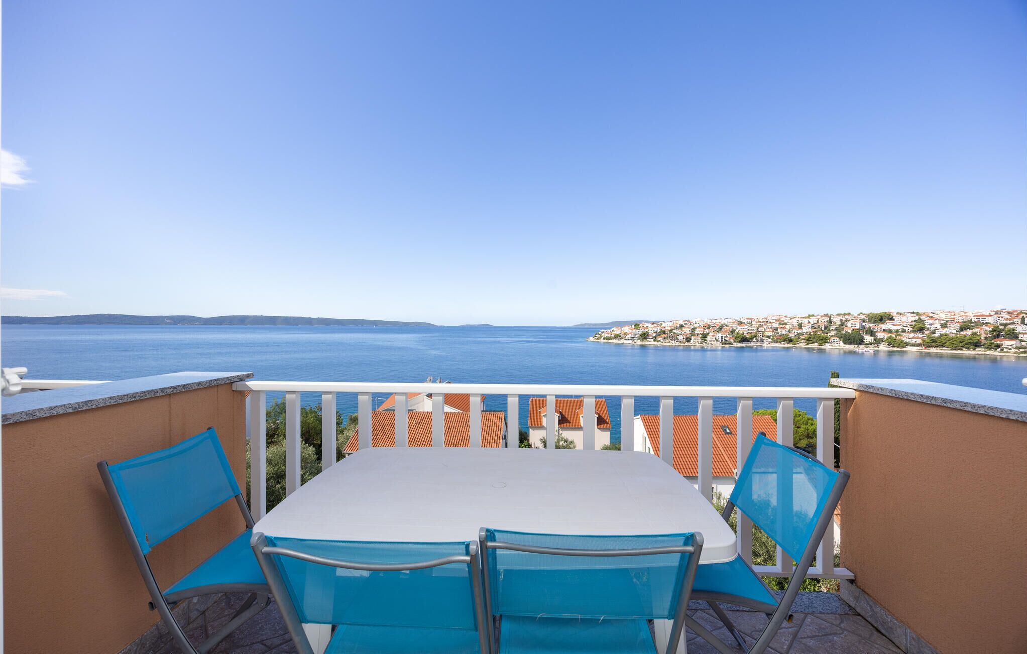 Balcón con mesa y sillas con vista al mar.
