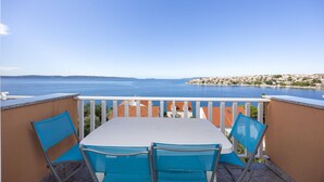 Un balcon avec une table et des chaises donnant sur une vue panoramique de la côte.
