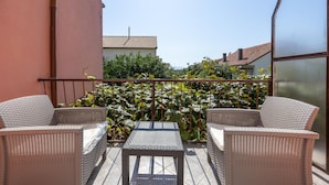 Un balcón con mobiliario de mimbre y vista a un jardín.