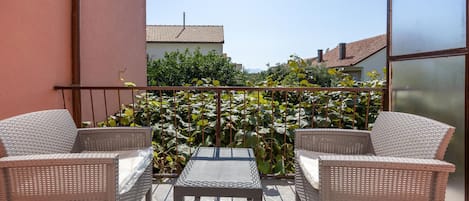 A balcony with wicker furniture and a view of a garden.