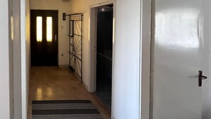 Un pasillo con un rug rectangular a rayas negras y blancas, una reja metálica y una puerta con picaporte.