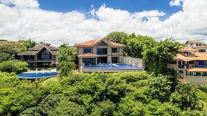 A large, two-story house with a swimming pool and lush greenery.