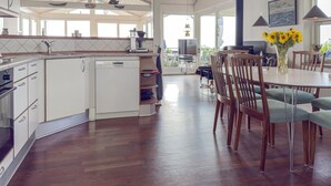 A spacious kitchen with white cabinetry, a dishwasher, and a dining area with wooden chairs and a table. - Stunning home in Ebeltoft with sauna (Ebeltoft)