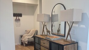 Et moderne soveværelse med en trækommode, et gulvtæppe med zebra-mønster, et spejl og en loftlampe.