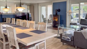A modern living room with a dining area, a fireplace, and a glass coffee table.