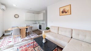 Un salon moderne comprenant un canapé, une table basse et un coin repas avec des chaises et une table en bois.