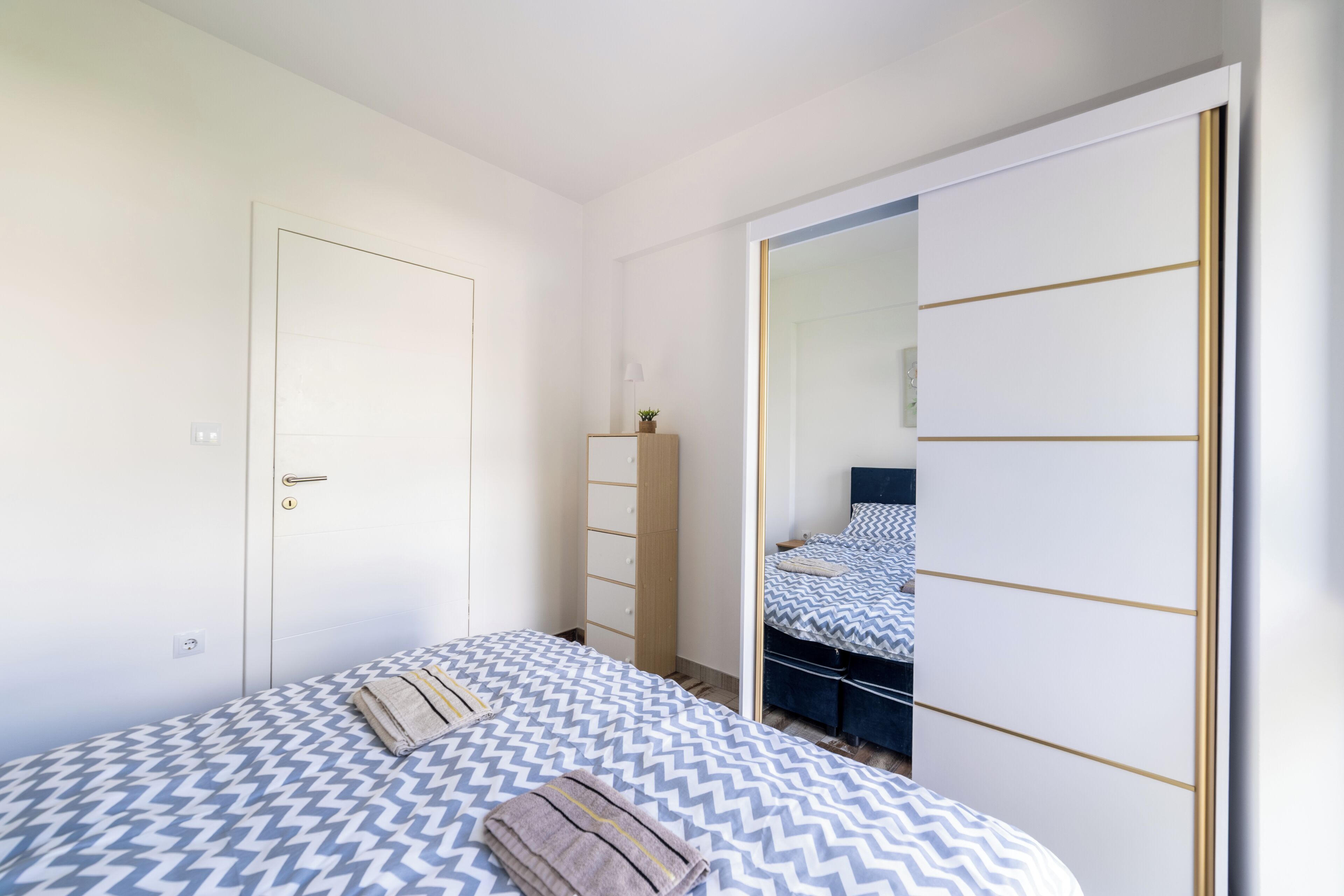 Una camera da letto con un letto, un armadio, uno specchio e un comò.