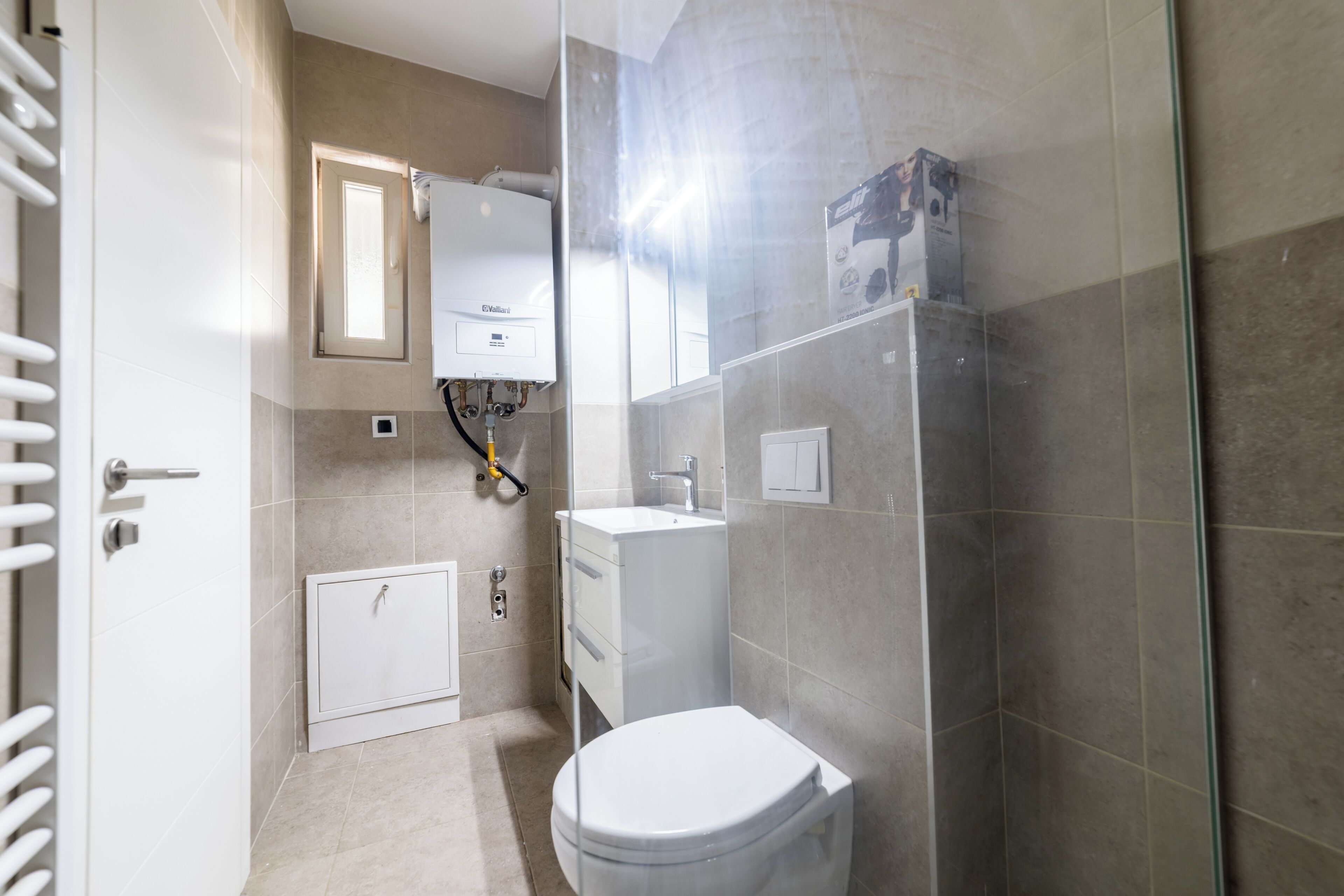 A compact bathroom with a toilet, sink, and shower.