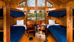 Une cabine équipée de deux lits superposés, d’un petit bureau et d’une fenêtre donnant sur un paysage verdoyant.