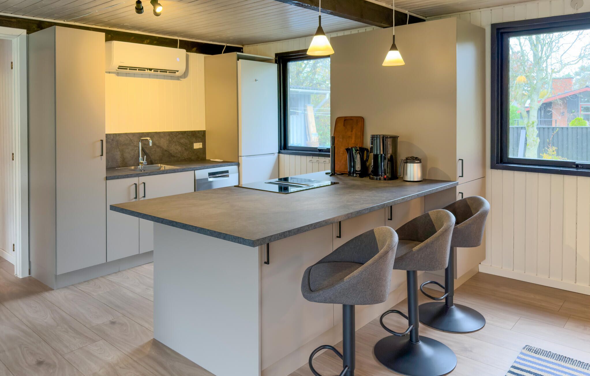 A modern kitchen with a central island, bar stools, and a window providing natural light.