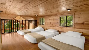 Une cabine avec trois lits, des murs en bois et un balcon doté d’une balustrade.