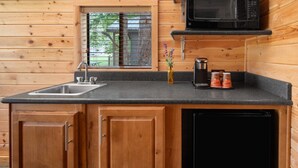 A compact kitchen with wooden walls, a sink, a microwave, and a coffee maker. - Central Cabin + Queen + Firepit | No Hidden Fees (Santa Barbara)