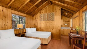 Een houten chalet met twee bedden, een eettafel en een keukenhoek.