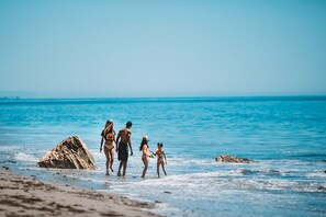 Eine Strandansicht mit einer großen Felsformation und ruhiger See.