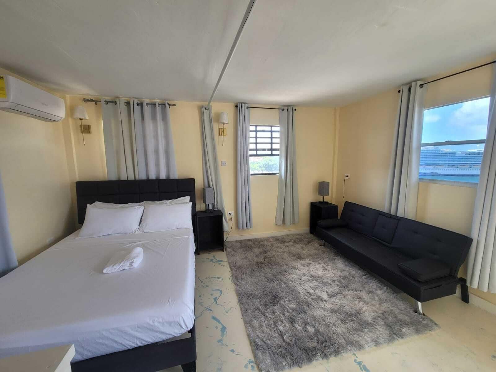 Une chambre d’hôtel avec un lit, un canapé, un tapis et une fenêtre donnant sur un paysage agréable.